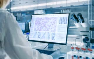 Photo of a person in a lab analyzing results on a screen